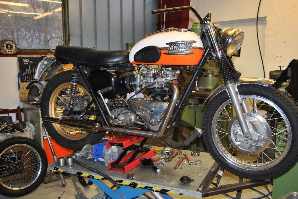 Ein weißes und orangenes Vintage Motorrad wird gewartet
